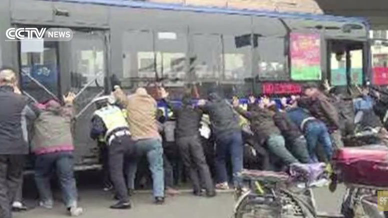 Watch a group of people lift a bus off a trapped man